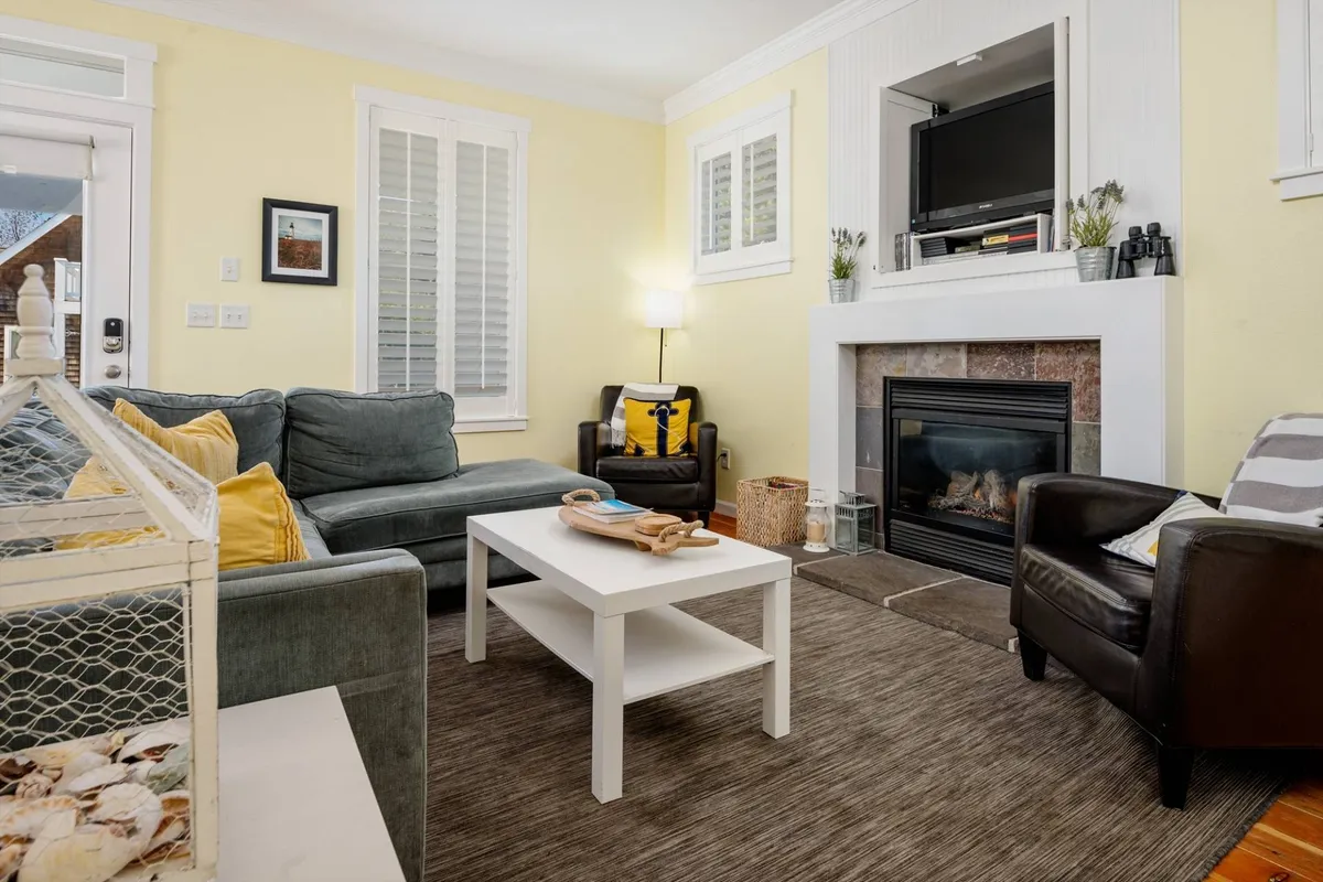 A cozy living room corner showcasing a gas fireplace with a modern surround, comfortable sofa seating, and a central coffee table. The scene is set for relaxation or movie nights, with a warm, inviting mood.