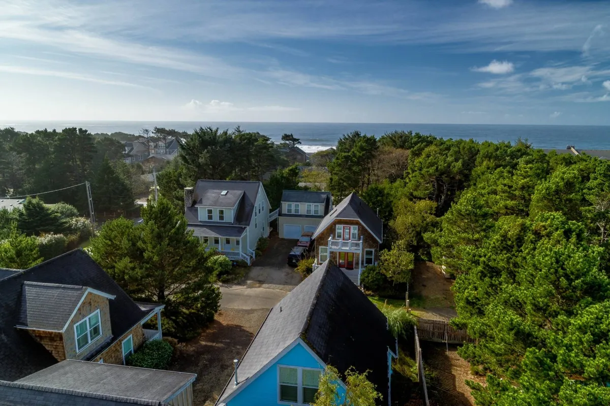 This image captures an inviting ocean view framed by a tree line, with the roofs of houses nestled in the foreground. The relaxed atmosphere and visible proximity of the beach highlight the neighborhood’s coastal charm. Family activities like beachcombing and gatherings are suggested by the layout and scenery.