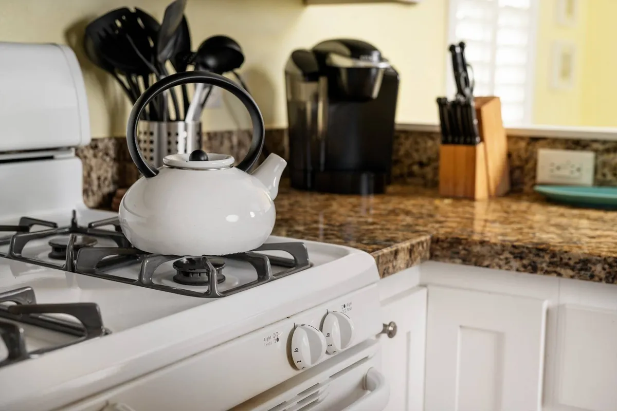 A cozy kitchen scene featuring a white kettle, granite countertop, and coffee maker, set up for a relaxed morning. The space is bright and functional, ideal for preparing breakfast or sharing a warm drink together before venturing out.